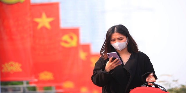 A woman wearing face mask looks at her phone in Hanoi, Vietnam.  (AP Photo/Hau Dinh, File)